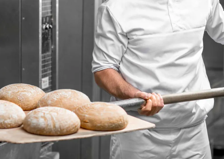 EDEKA-Partner und Produktionsbetriebe - Bäcker, der Brot aus dem Ofen holt.