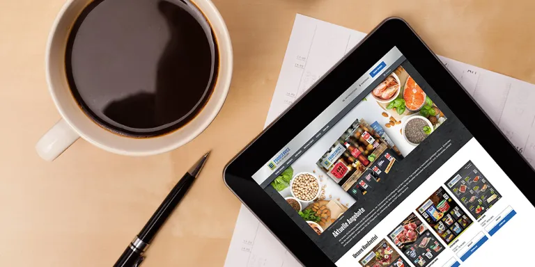 Tisch mit Kaffeetasse und iPad, Newsletter auf Screen sichbar
