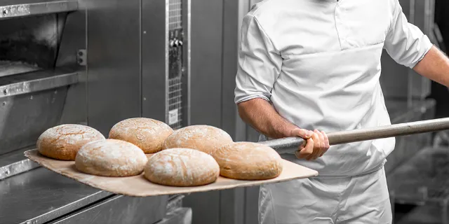 EDEKA-Partner und Produktionsbetriebe - Bäcker, der Brot aus dem Ofen holt