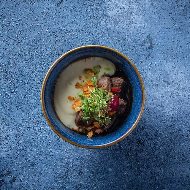 Kleine Schale mit Essen serviert auf blauen Hintergrund.  