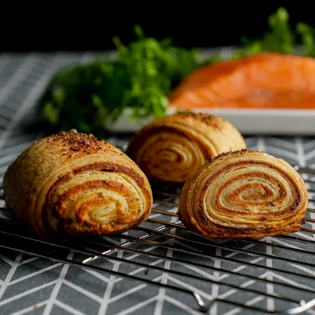 Knusprige Blätterteigrollen  liegen auf einem Backblech. 